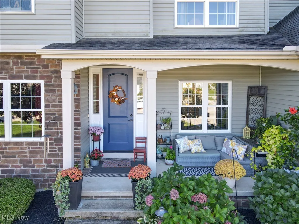 Entrance to property featuring a shingled roof, a porch, outdoor lounge area, and stone siding