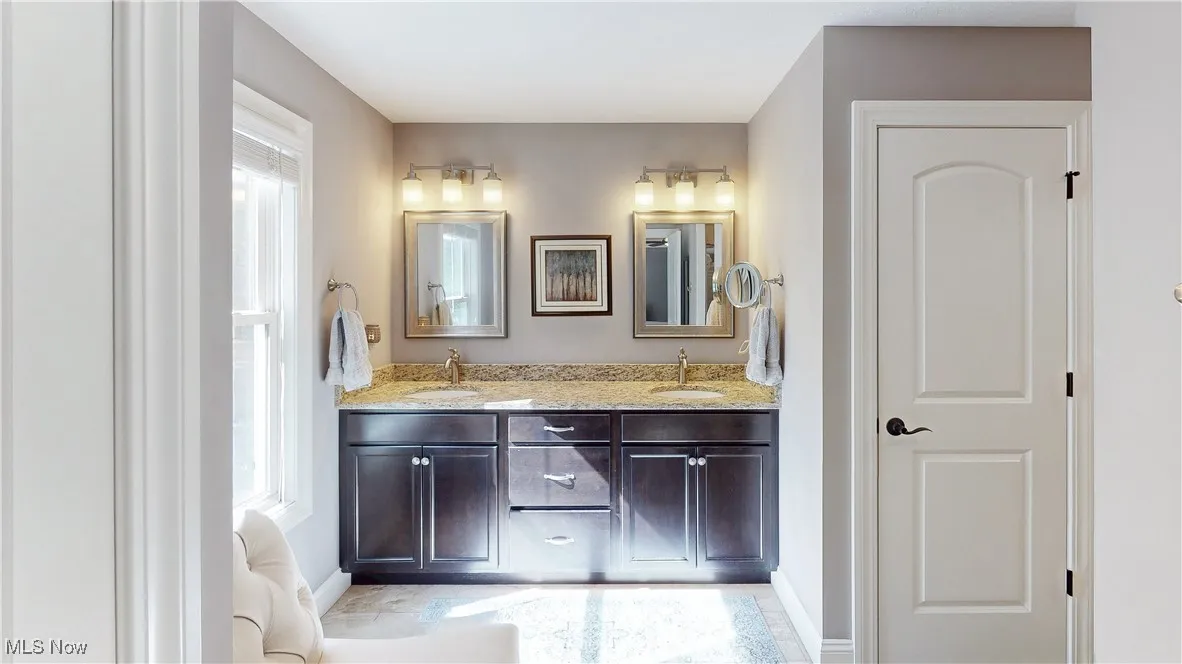 Full bathroom featuring double vanity and baseboards