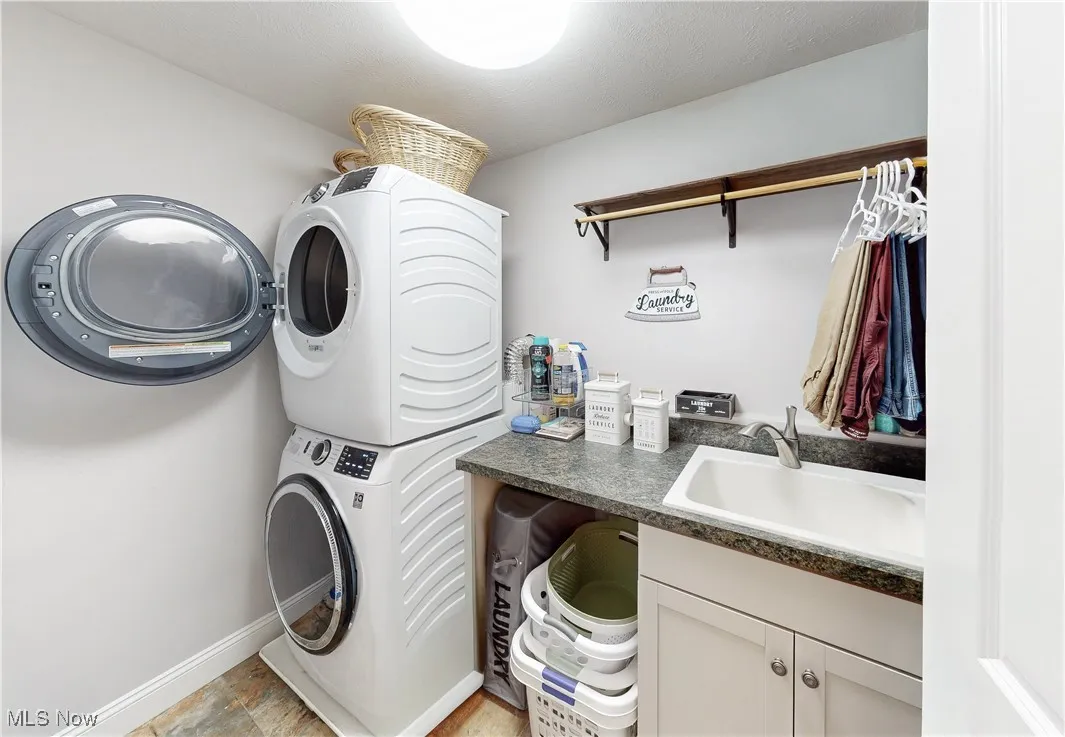 Laundry area with stacked washer / dryer and a sink