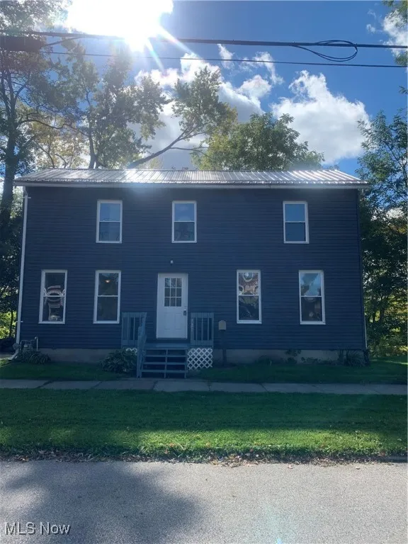 View of front of property with a metal roof and a front lawn