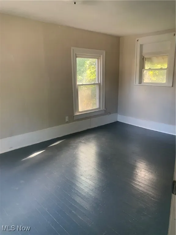 Spare room with dark wood-style floors and baseboards