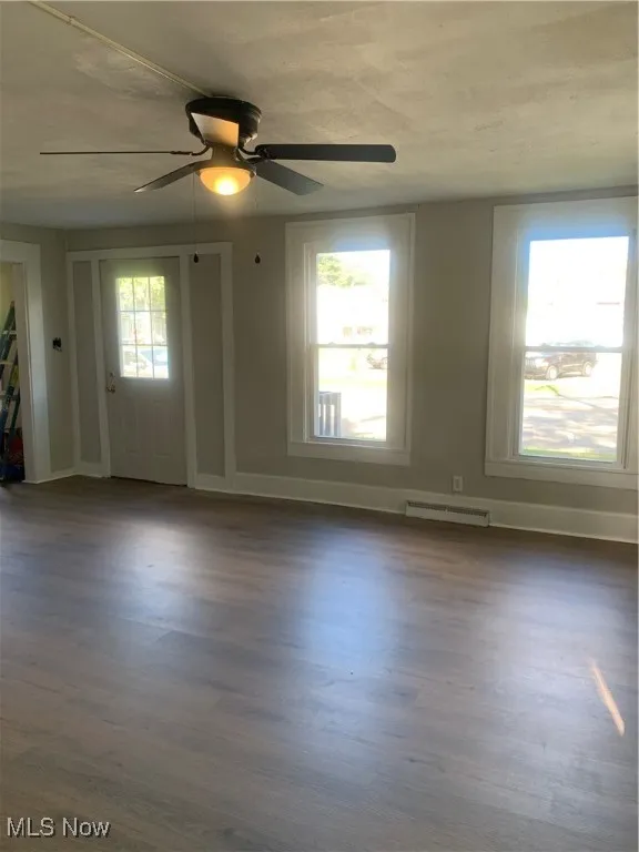 Spare room with dark wood-style flooring, healthy amount of natural light, and ceiling fan