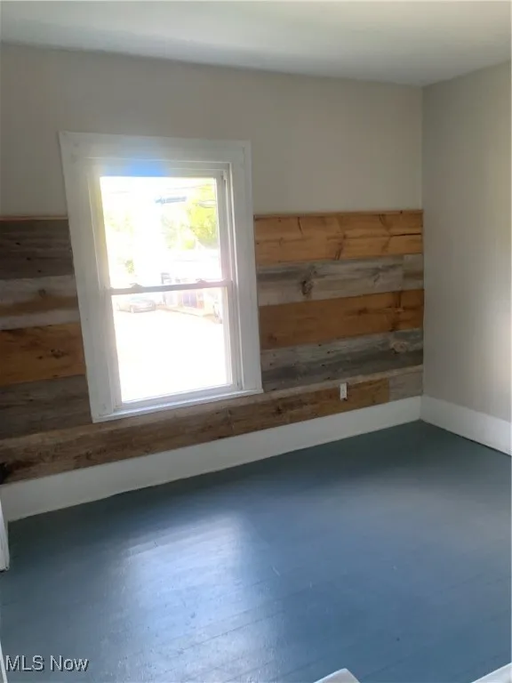 Empty room with dark wood-type flooring and wooden walls