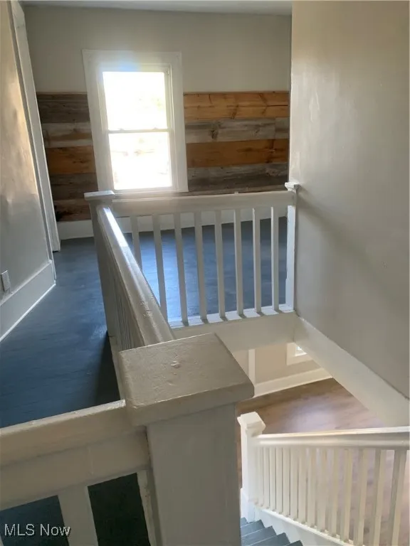 Stairway featuring wooden walls and wood finished floors