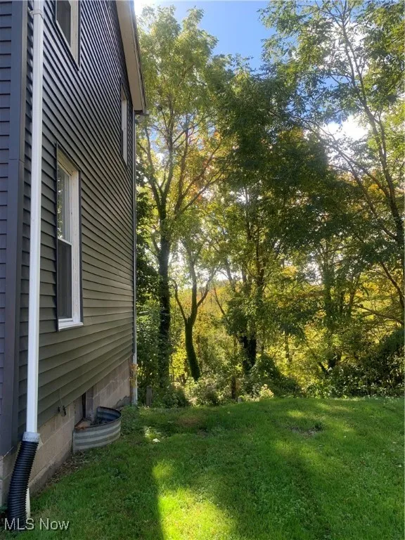 View of grassy yard featuring view of scattered trees