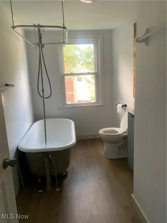 Full bath featuring wooden walls and dark wood finished floors