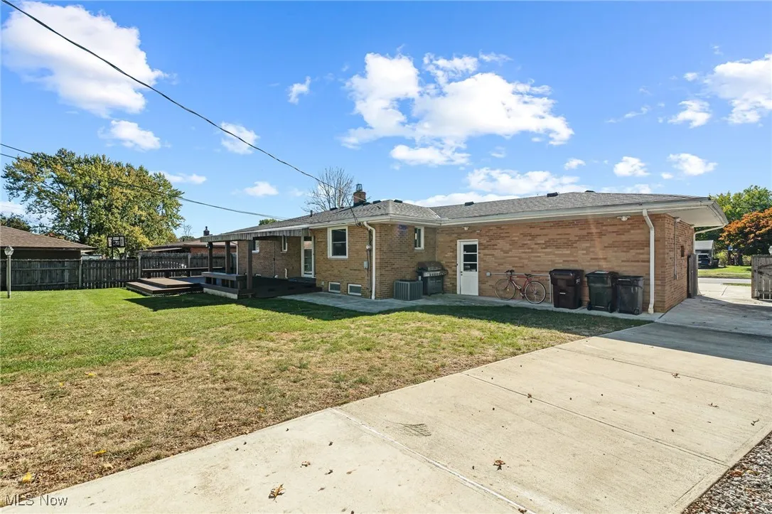Rear view of property with brick siding, a fenced backyard, a patio area, a chimney, and a wooden deck