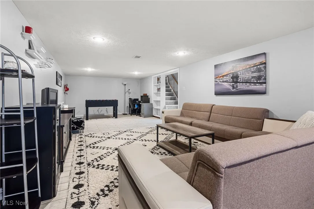 Living room with a textured ceiling, stairway, and light tile patterned floors