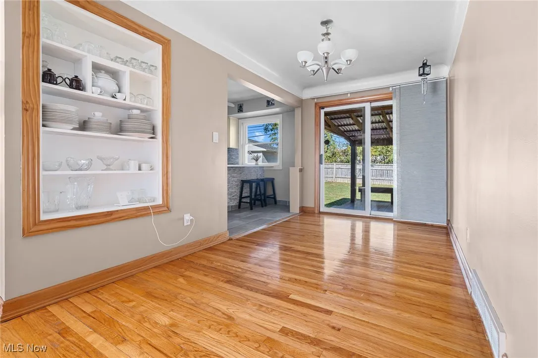 Unfurnished dining area with built in shelves, light wood finished floors, and a chandelier