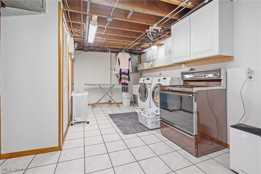 Washroom with washer and dryer, light tile patterned floors, and electric panel