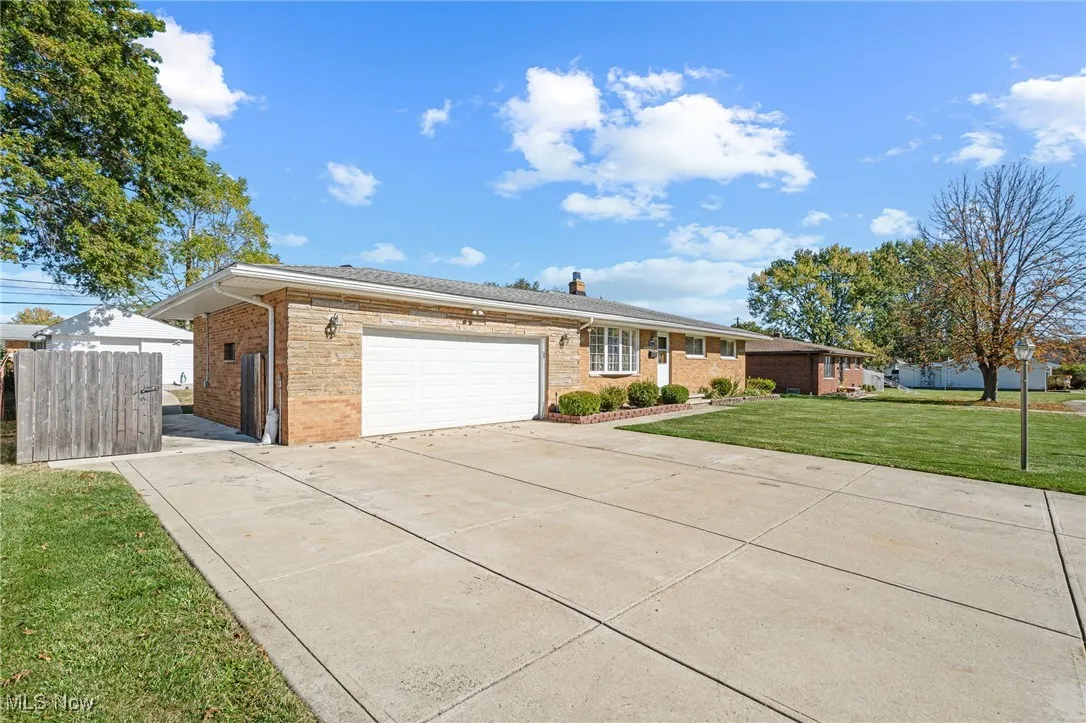 Ranch-style home featuring a front yard, a garage, concrete driveway, and brick siding