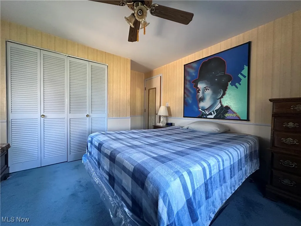 Carpeted bedroom featuring ceiling fan and a closet