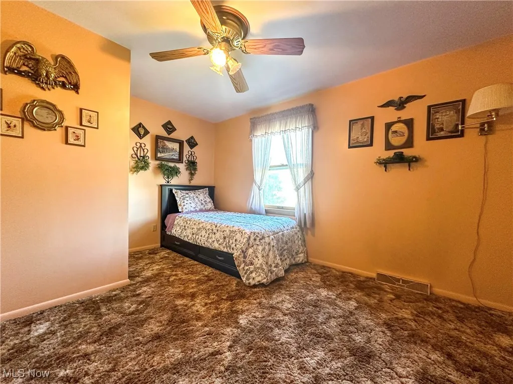 Bedroom with dark carpet and ceiling fan