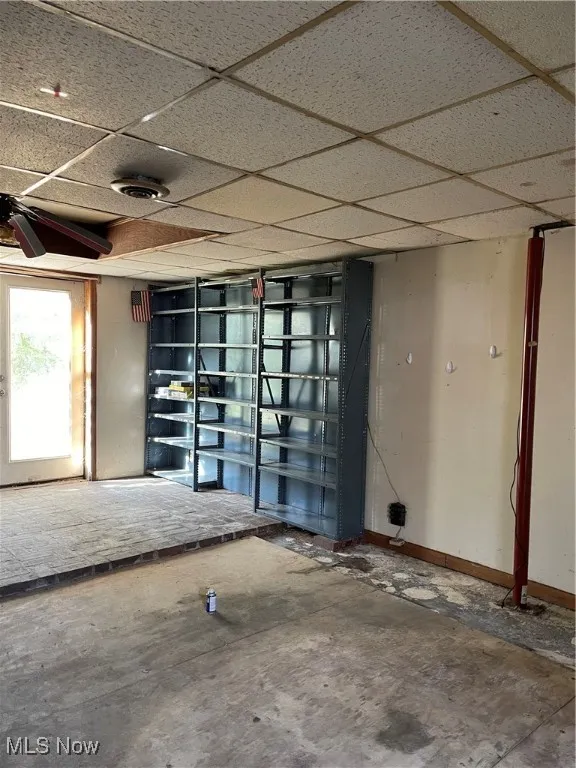 Empty room featuring unfinished concrete flooring, ceiling fan, and a paneled ceiling