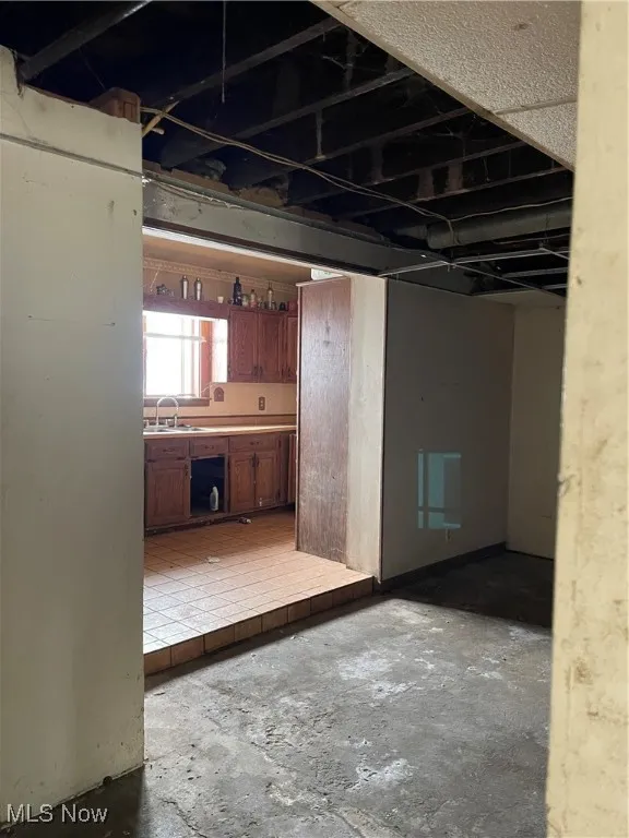 Kitchen featuring light countertops, brown cabinets, and unfinished concrete flooring