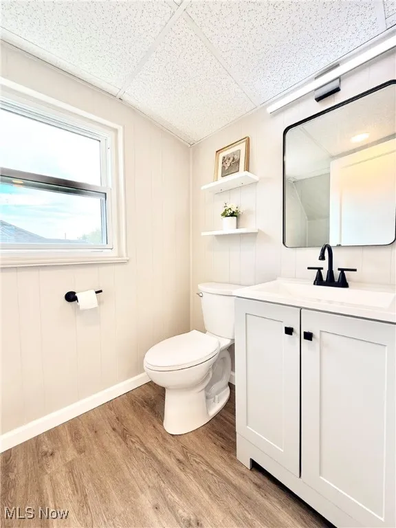 Half bathroom with light wood finished floors, vanity, and a paneled ceiling