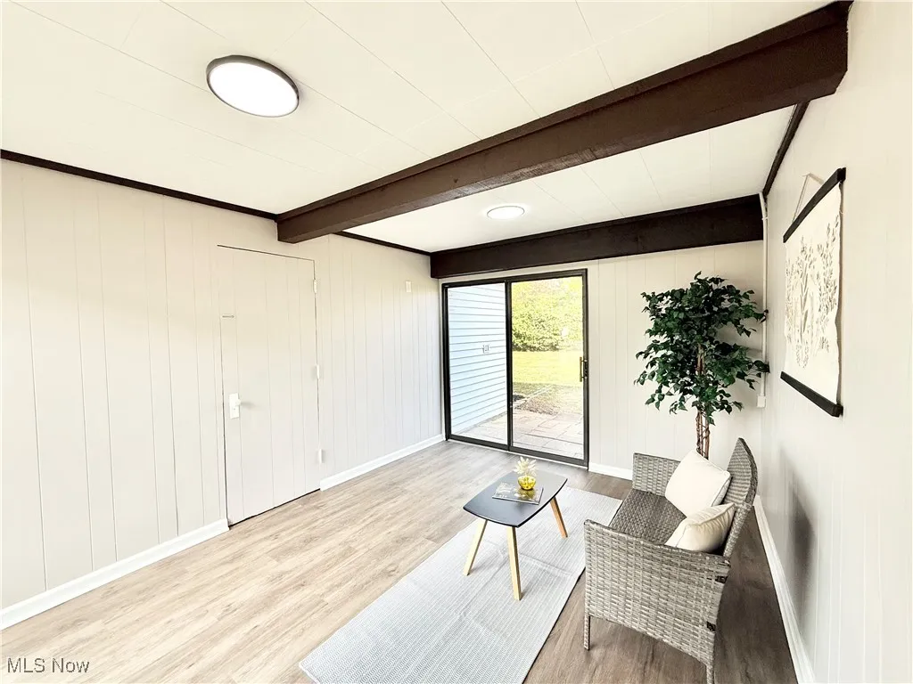 Sitting room with wood finished floors, beam ceiling, and wooden walls