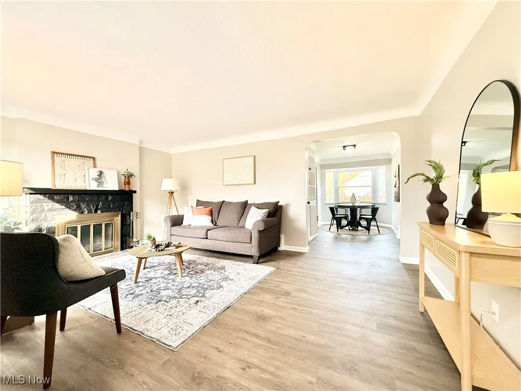 Living room with light wood-style flooring, a glass covered fireplace, and arched walkways
