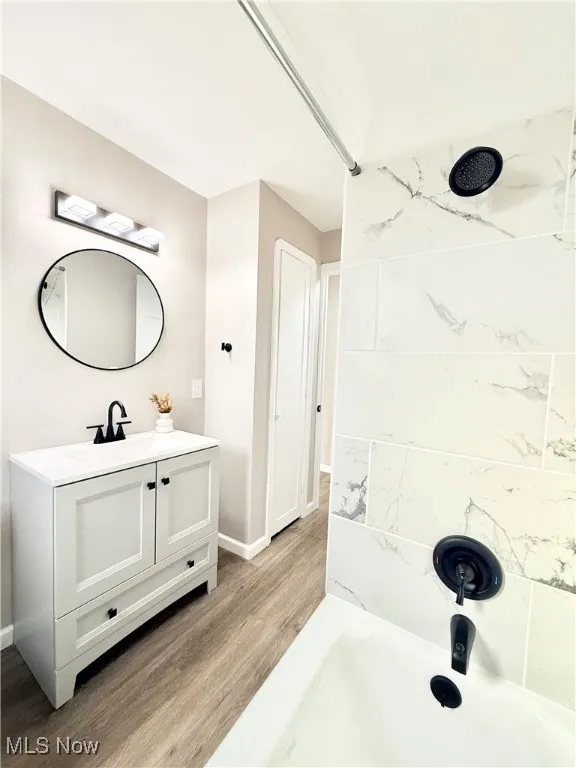 Full bath with vanity, light wood finished floors, and tub / shower combination