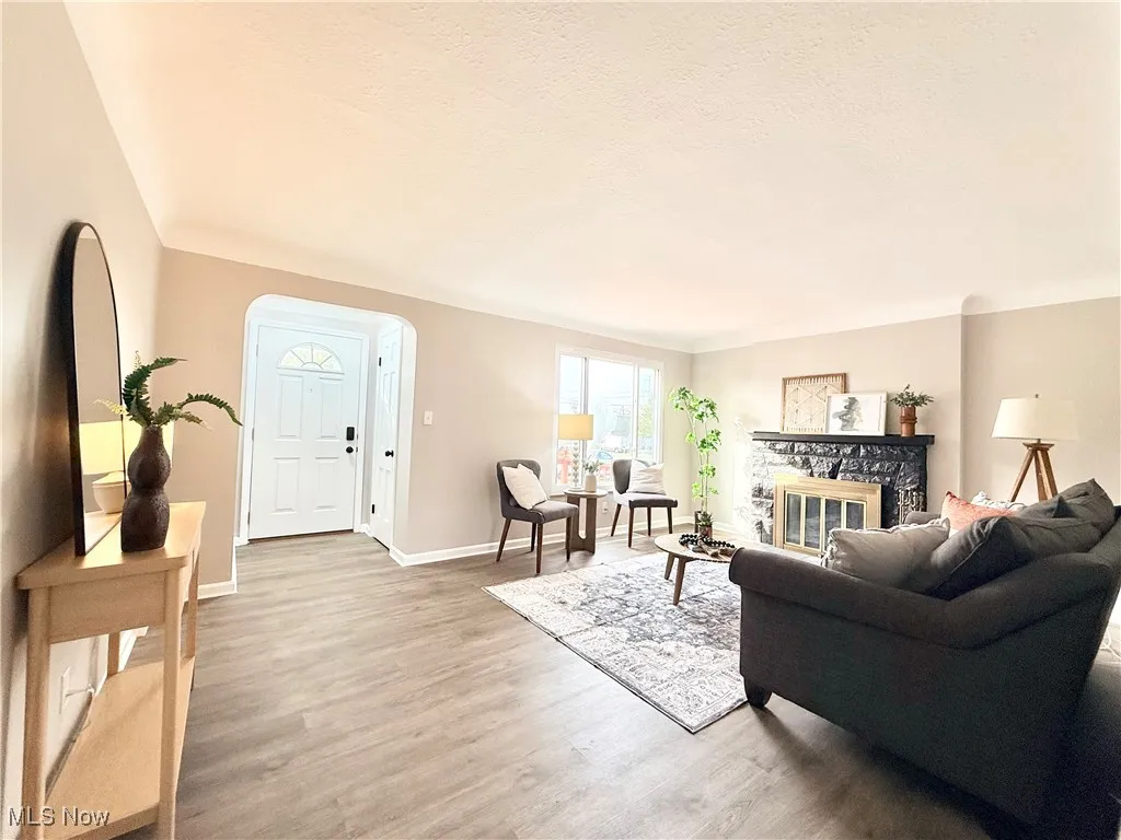 Living area featuring light wood-type flooring, a glass covered fireplace, and a textured ceiling