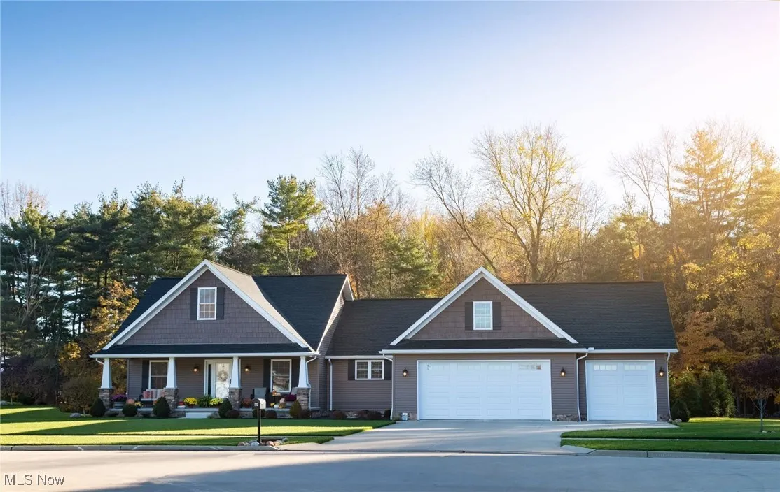 Craftsman-style home featuring a porch, a front yard, driveway, and a garage