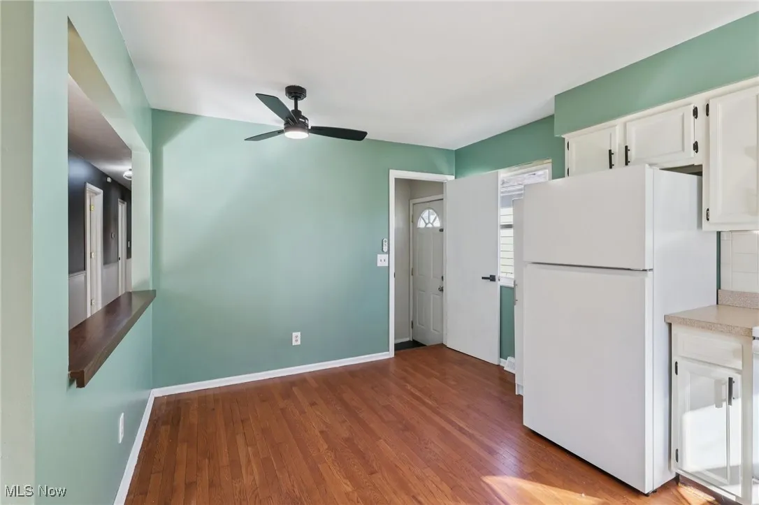 Kitchen with white cabinets, freestanding refrigerator, light wood-style flooring, light countertops, and ceiling fan