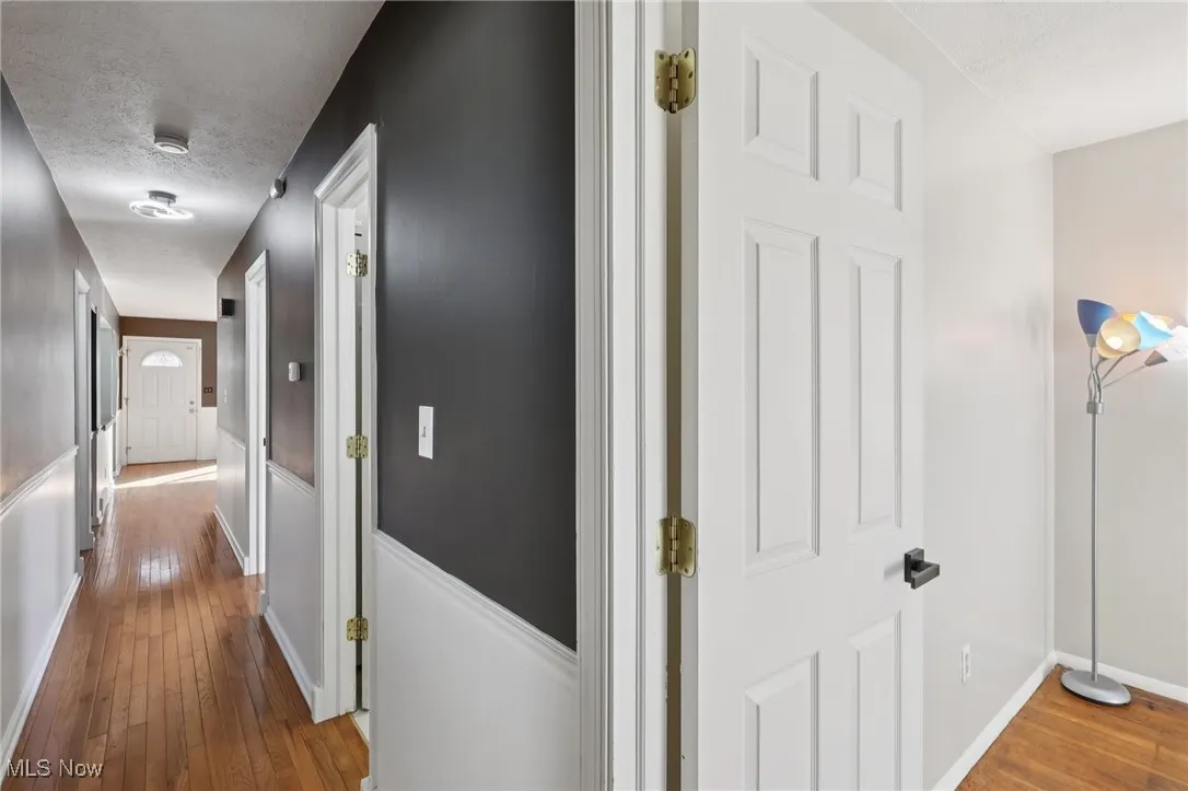 Corridor with light wood-style flooring and a textured ceiling