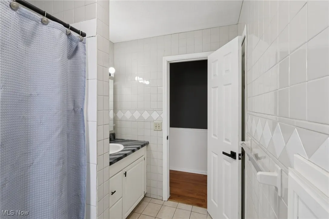 Full bathroom featuring tile walls, a shower stall, vanity, and light tile patterned floors