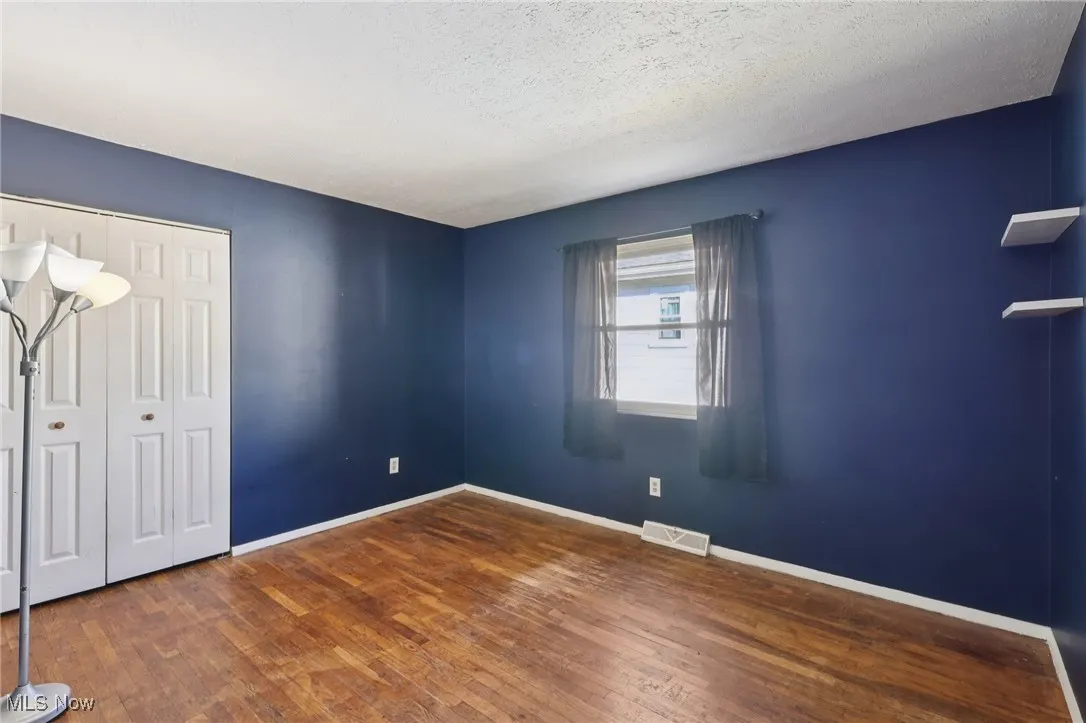 Unfurnished bedroom featuring a closet, dark wood-style floors, and a textured ceiling