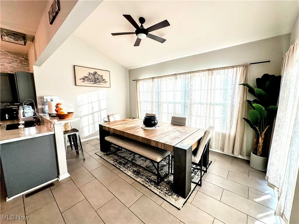 Dining space with lofted ceiling, light tile patterned floors, and ceiling fan