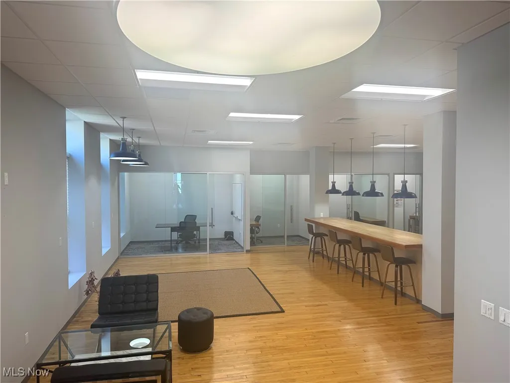 Exercise area with light wood-type flooring and a drop ceiling