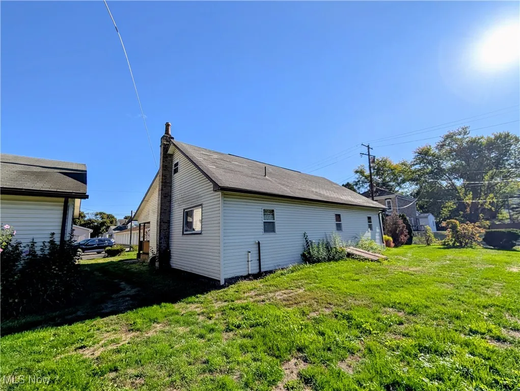 Rear view of property featuring a lawn and a chimney