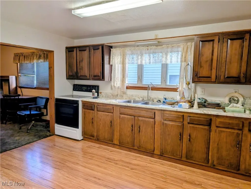 Kitchen featuring light countertops, electric stove, and light wood-style floors