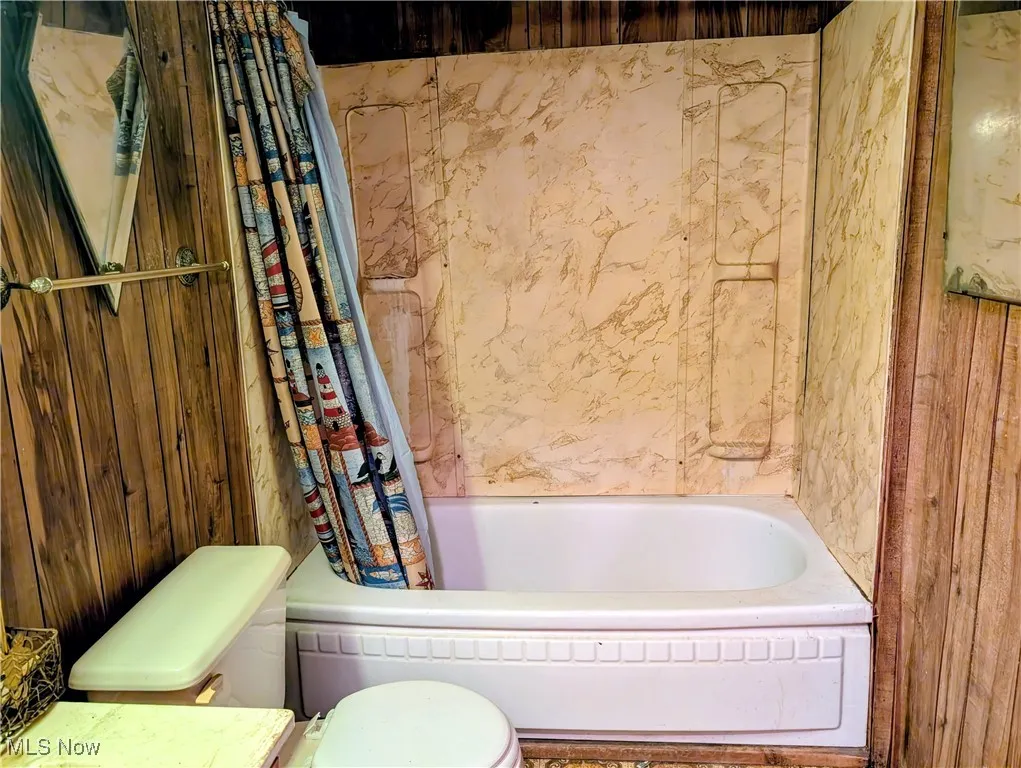 Full bathroom featuring toilet and shower / bath combo with shower curtain