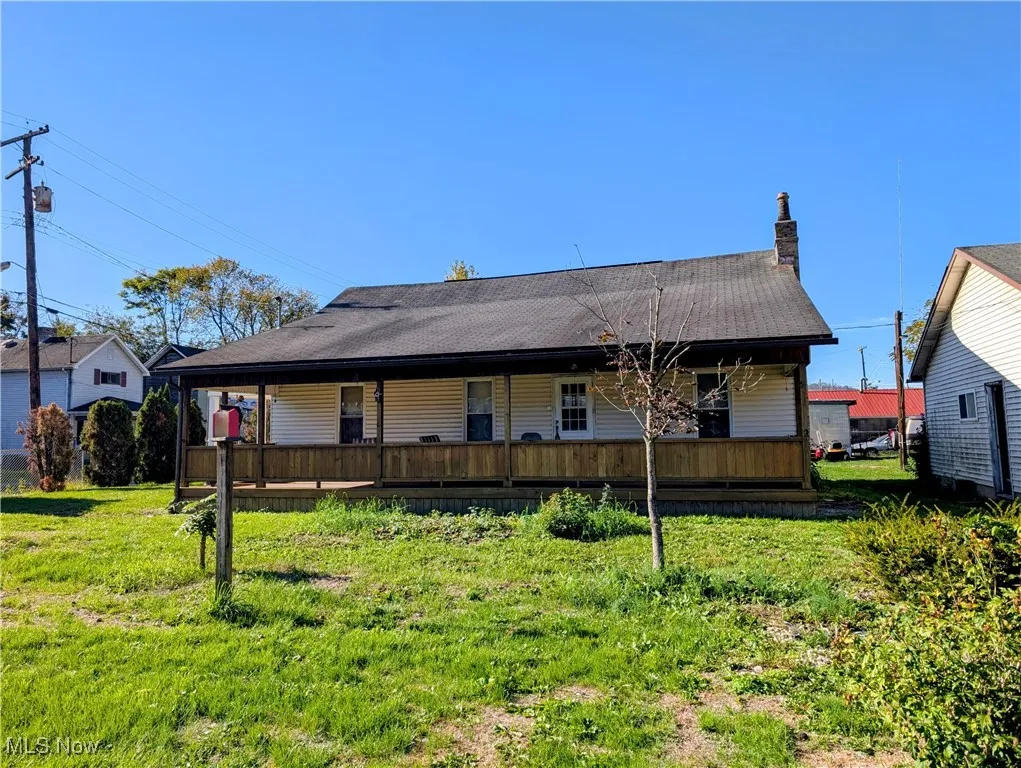 Back of house with a lawn, a chimney, and a shingled roof