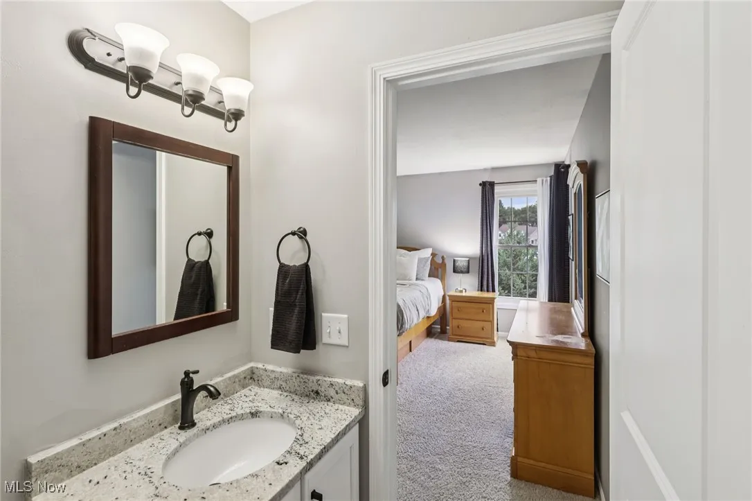 Bathroom featuring lvt flooring, vanity, and connected bedroom