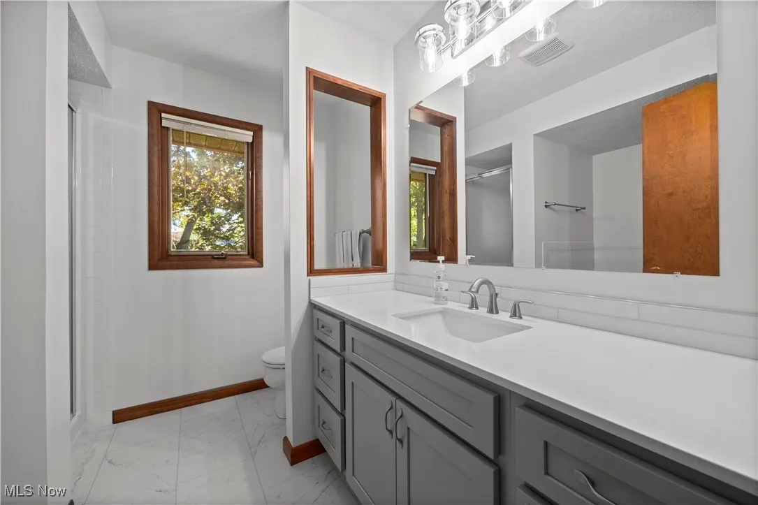 Full bath with vanity, light marble finish flooring, and a shower stall