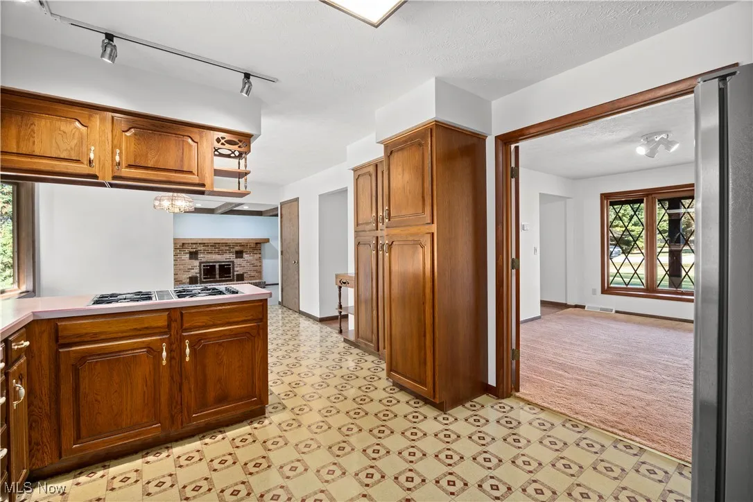 Kitchen featuring brown cabinets, light countertops, appliances with stainless steel finishes, light flooring, and track lighting