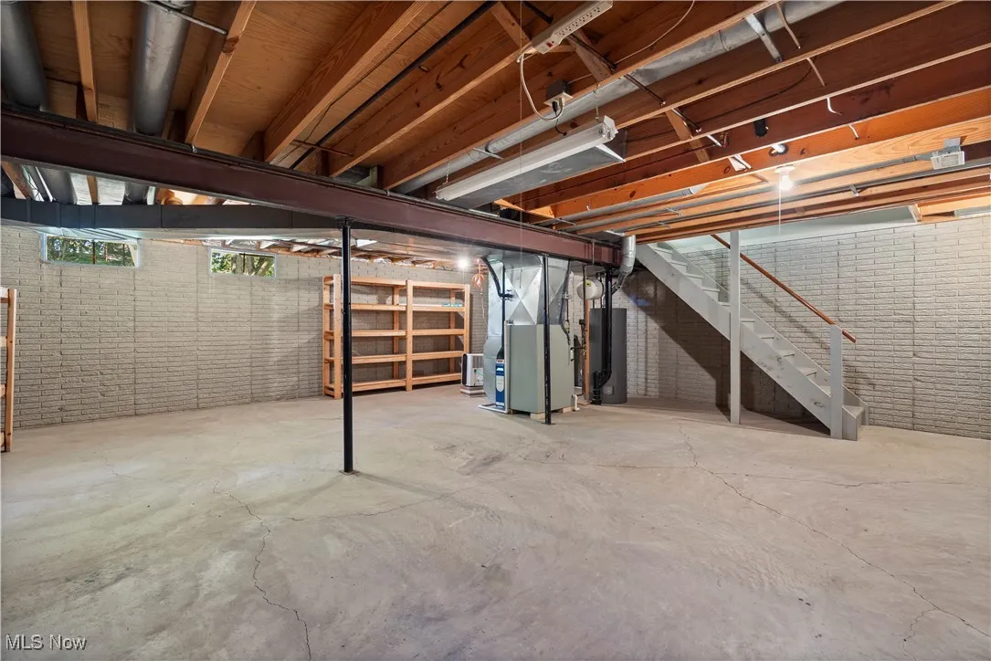 Basement with stairway, water heater, and heating unit