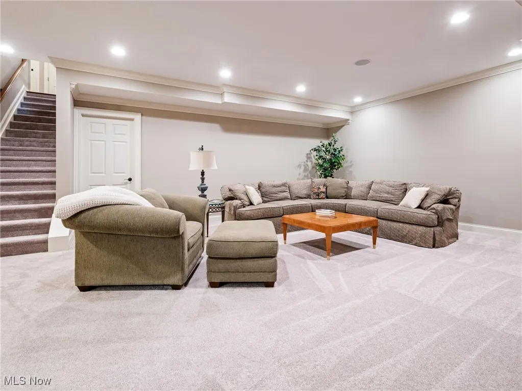 Carpeted living area featuring recessed lighting, ornamental molding, and stairway