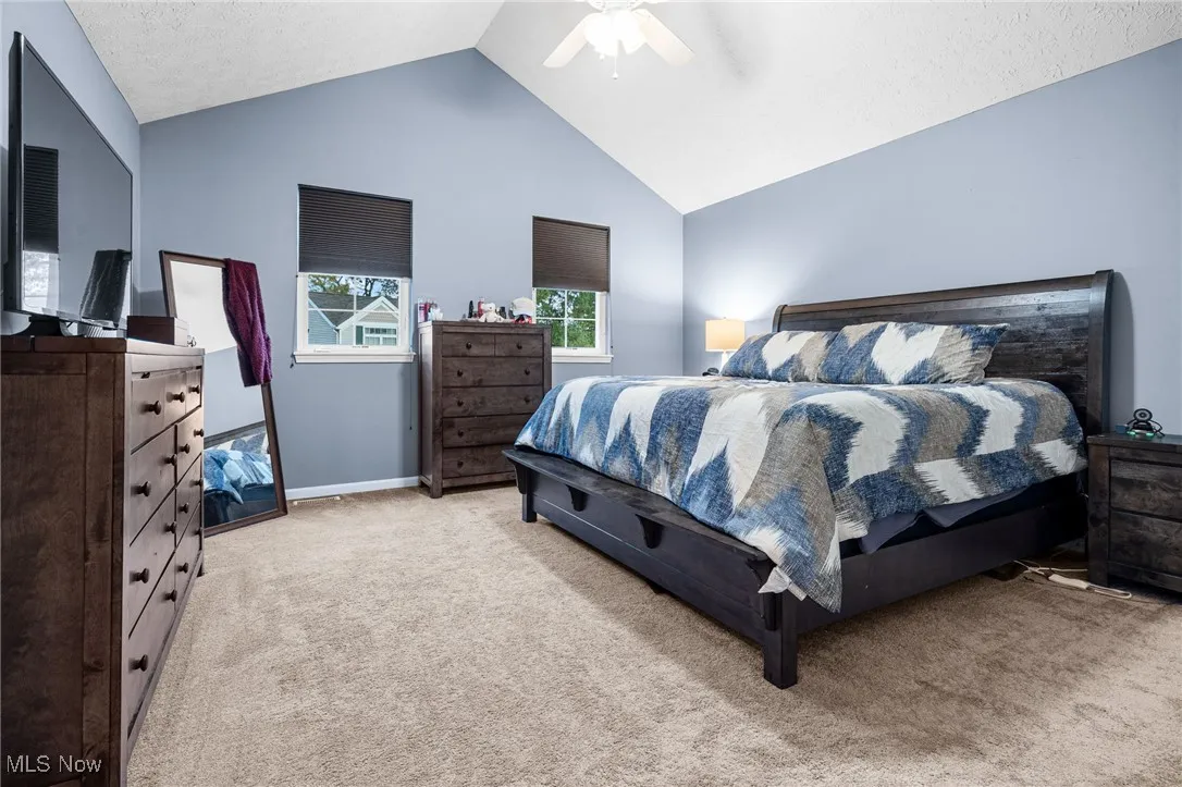 Bedroom with carpet floors, lofted ceiling, a textured ceiling, and ceiling fan