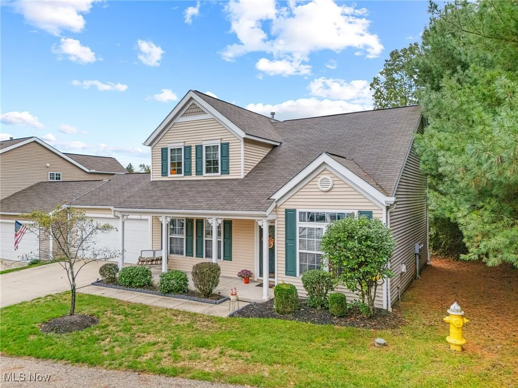 Traditional home featuring covered porch, concrete driveway, an attached garage, a shingled roof, and a front lawn