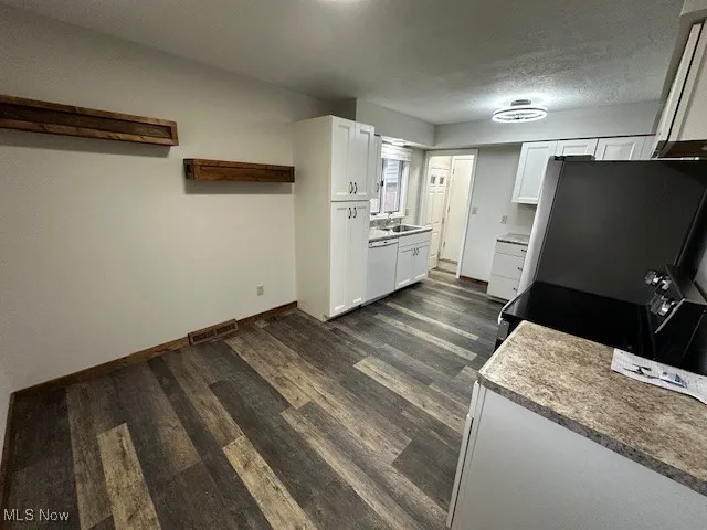 Kitchen with white cabinetry, dark wood-type flooring, light countertops, and a textured ceiling