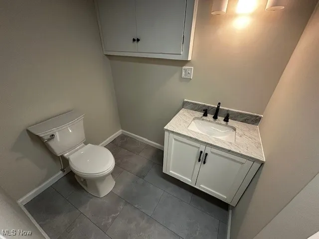 Half bath featuring vanity and dark tile patterned flooring