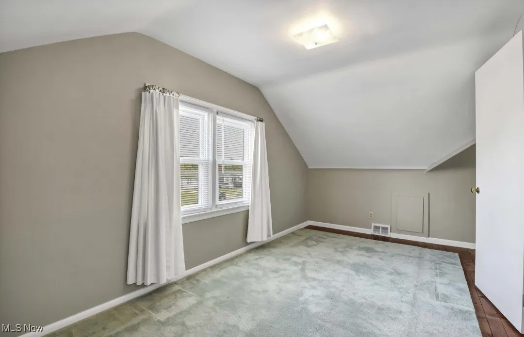 Additional living space with vaulted ceiling and carpet flooring