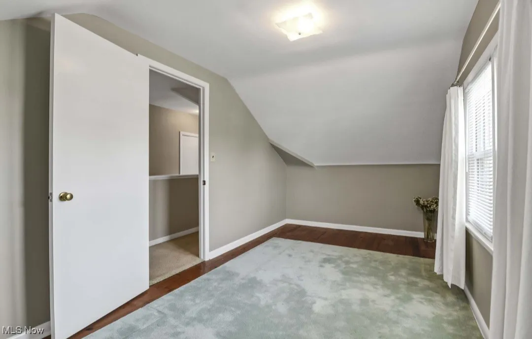 Additional living space featuring vaulted ceiling and dark wood-style flooring