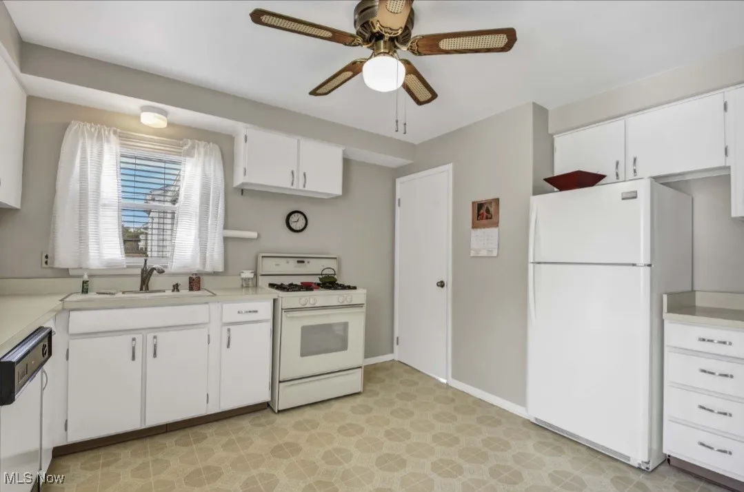 Kitchen featuring white appliances, light countertops, white cabinets, and a ceiling fan