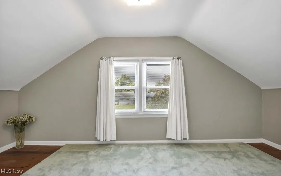 Additional living space with lofted ceiling and dark wood-style floors
