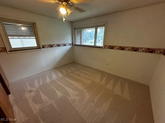 Carpeted empty room with a ceiling fan