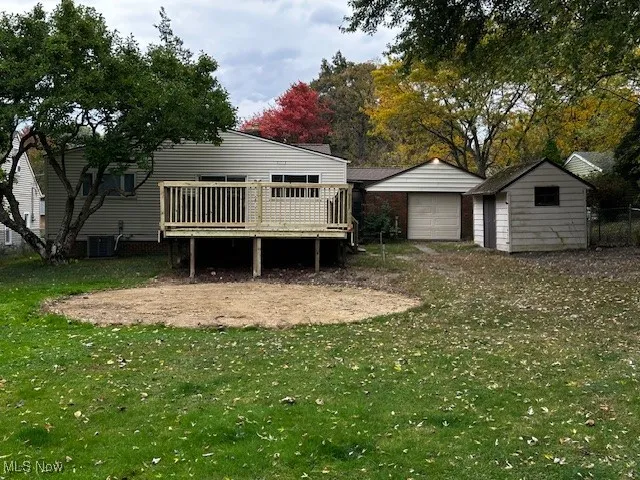 View of grassy yard with a wooden deck, an outdoor structure, and a detached garage